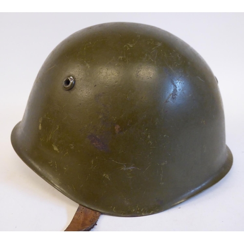 87 - A German World War II era, khaki painted military helmet with a hide liner and buckled chinstrap(Ple... 