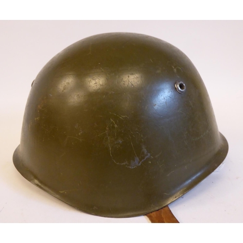 87 - A German World War II era, khaki painted military helmet with a hide liner and buckled chinstrap(Ple... 