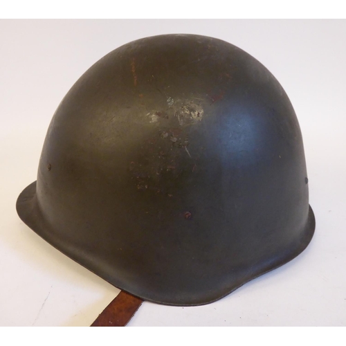 91 - A mid 20thC Eastern European dark green painted steel military helmet, bears the remnants of a paint... 