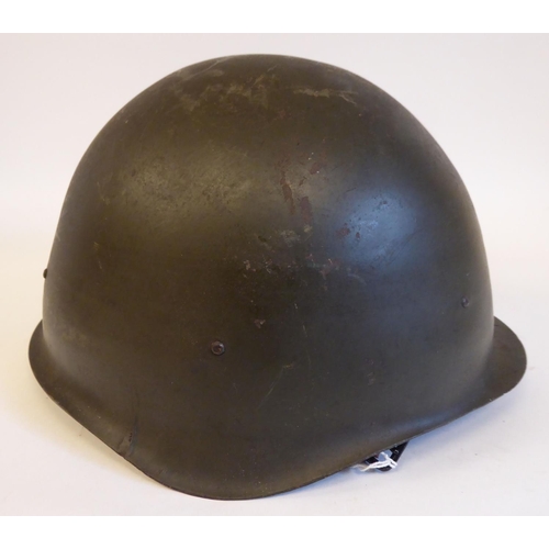 91 - A mid 20thC Eastern European dark green painted steel military helmet, bears the remnants of a paint... 