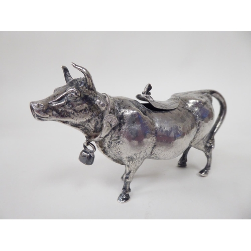 93 - A 19thC Continental silver coloured metal cow creamer, the hinged cap incorporating a bee finial, th... 