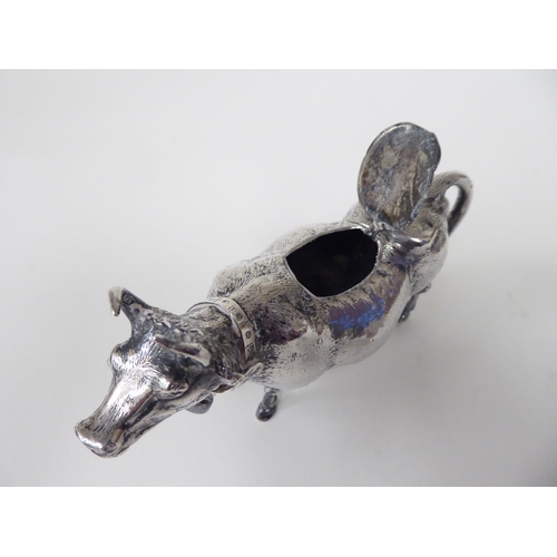 93 - A 19thC Continental silver coloured metal cow creamer, the hinged cap incorporating a bee finial, th... 