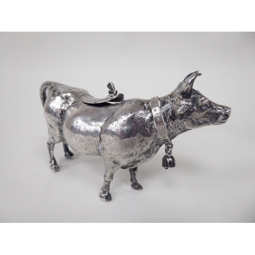 93 - A 19thC Continental silver coloured metal cow creamer, the hinged cap incorporating a bee finial, th... 