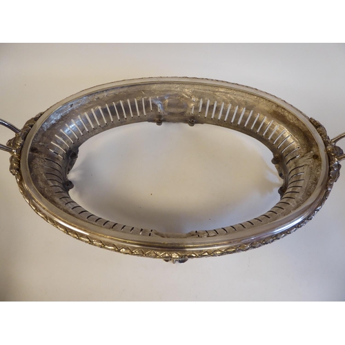 98 - An early 20thC silver plated, two-part serving dish of oval form, profusely cast with maskheads, pie... 