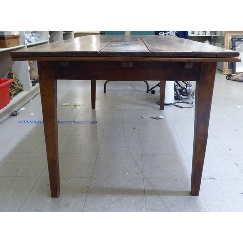 124 - A mid 19thC Continental cherrywood farmhouse table with a planked single end draw leaf, raised on sq... 