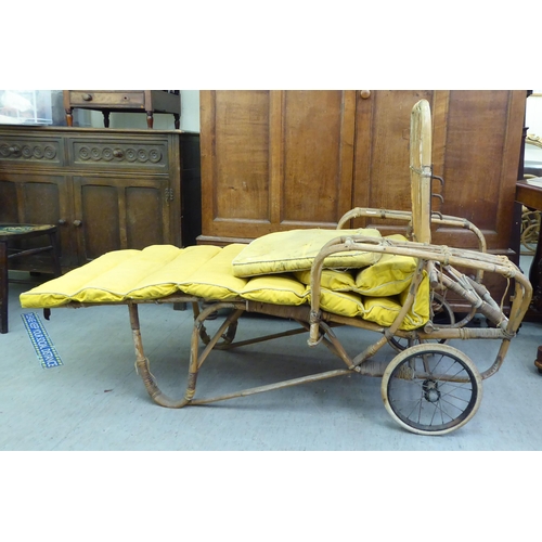 145 - A 1930s colonial design bamboo framed veranda day bed with an adjustable back and spoken wheels