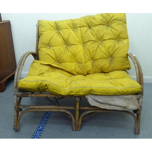 146 - A 1930s colonial design bamboo framed two person veranda settee with spoken wheels