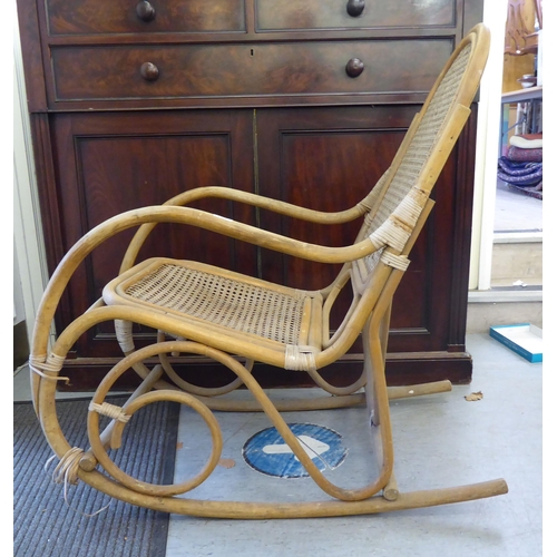 148 - A 1930s colonial design bamboo framed veranda rocking chair with a caned back and seat, raised on cu... 