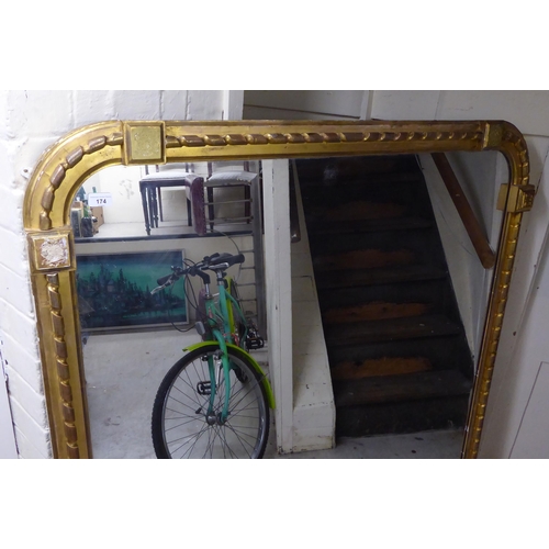 174 - A late Victorian overmantel mirror with a round arched top, in a rope effect, moulded giltwood frame... 