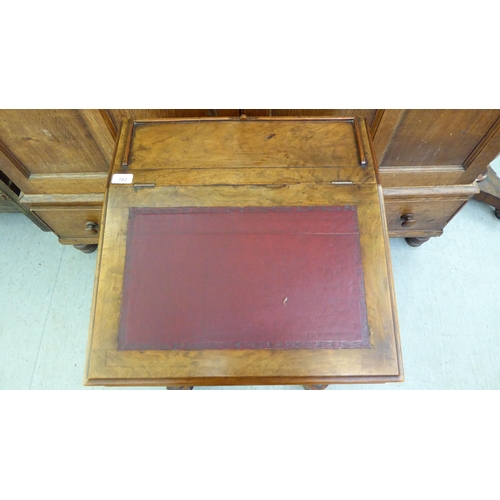 182 - A late Victorian walnut Davenport with a sloping hinged lid, set with a red hide scriber, over a pan... 