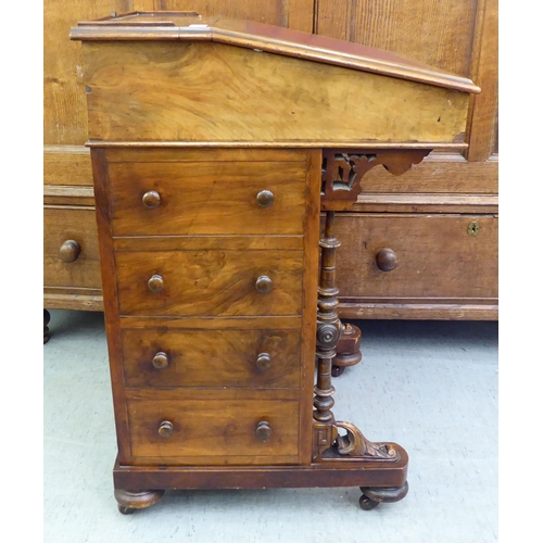 182 - A late Victorian walnut Davenport with a sloping hinged lid, set with a red hide scriber, over a pan... 