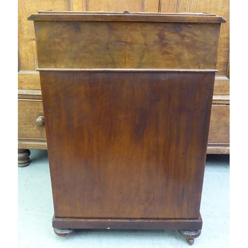 182 - A late Victorian walnut Davenport with a sloping hinged lid, set with a red hide scriber, over a pan... 