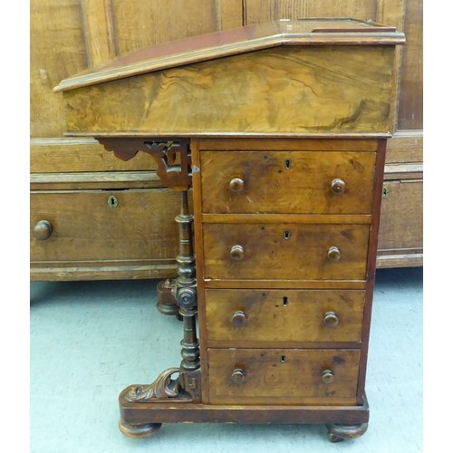 182 - A late Victorian walnut Davenport with a sloping hinged lid, set with a red hide scriber, over a pan... 