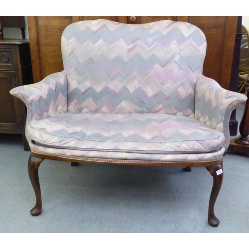 183 - A 1920s mahogany framed two person salon settee, upholstered in a multi-coloured fabric, raised on c... 