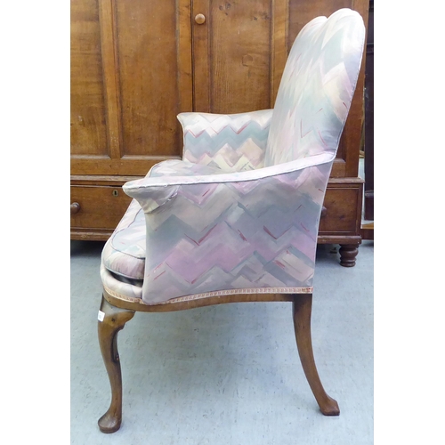 183 - A 1920s mahogany framed two person salon settee, upholstered in a multi-coloured fabric, raised on c... 