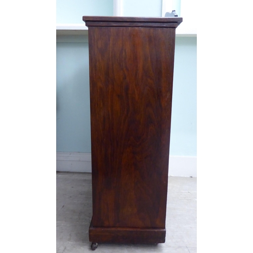 20 - An Edwardian string inlaid rosewood music cabinet with a panelled and glazed door, on a bracket plin... 