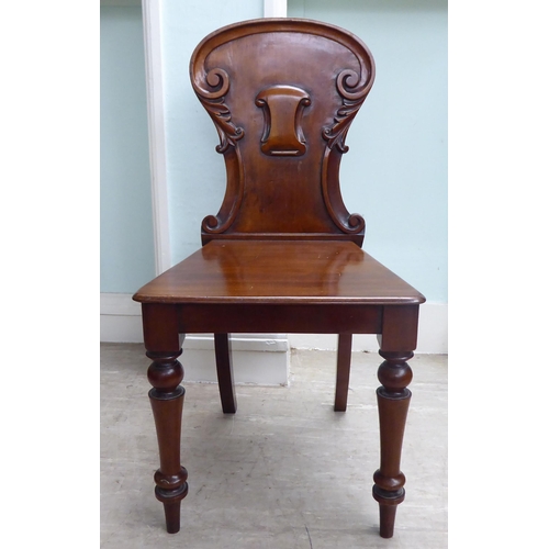 21 - A William IV mahogany panel back hall chair with a solid seat, raised on turned forelegs