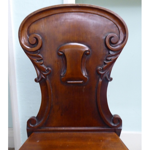 21 - A William IV mahogany panel back hall chair with a solid seat, raised on turned forelegs