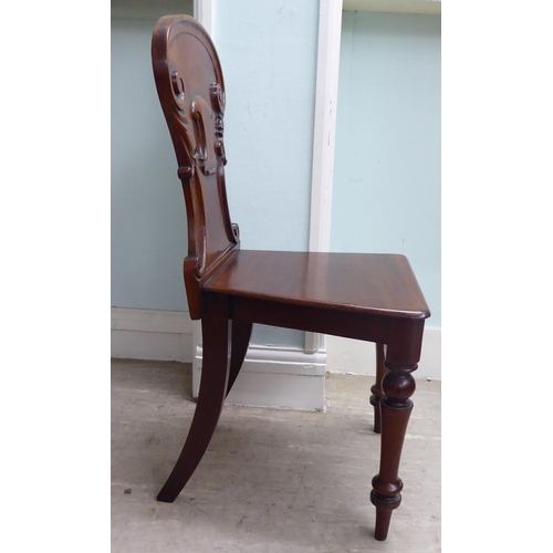 21 - A William IV mahogany panel back hall chair with a solid seat, raised on turned forelegs