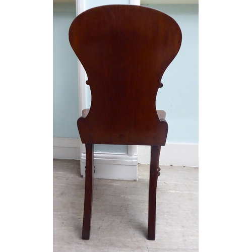 21 - A William IV mahogany panel back hall chair with a solid seat, raised on turned forelegs