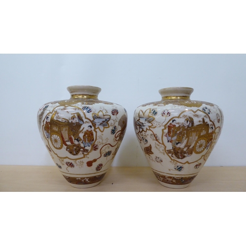 214 - A pair of early/mid 20thC Japanese Satsuma vases of tapered form, decorated with figures beside a ri... 