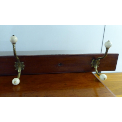 222 - A late Victorian hanging mahogany row of four decoratively cast brass hat and coat hooks with white ... 