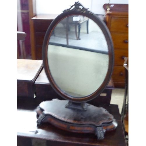 242 - A late Victorian oval mirror with an inlaid and brass finished mahogany frame, incorporating a folia... 