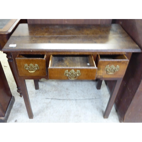 251 - A late 18thC oak lowboy, the planked top over three box drawers with brass handles on pierced backpl... 