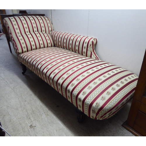 258 - A late Victorian day bed with a pillow back and side, upholstered in striped floral fabric, raised o... 