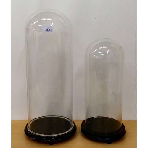 282 - Two glass clock domes, on plinths  21