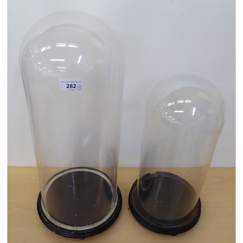 282 - Two glass clock domes, on plinths  21