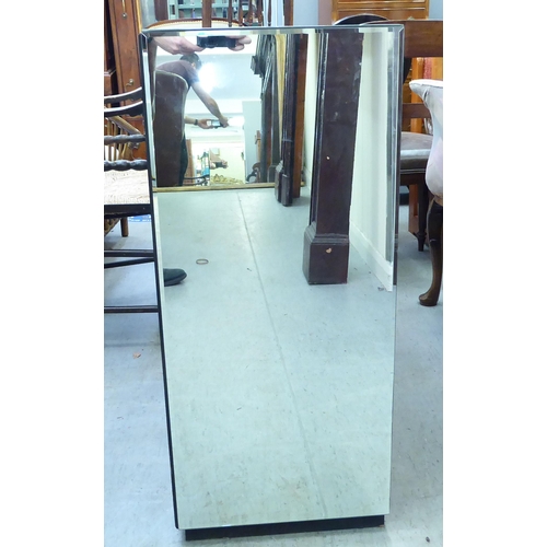 291 - A modern mirrored side cabinet with a pair of doors with stylised circular designs, on a plinth ... 