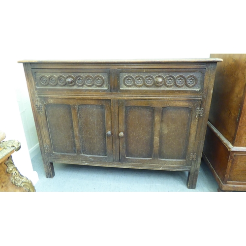 292 - An early 20thC stained oak sideboard with two frieze drawers, over two panelled doors, raised on str... 