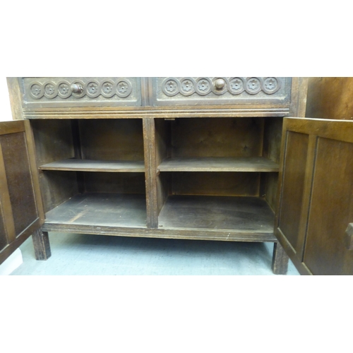 292 - An early 20thC stained oak sideboard with two frieze drawers, over two panelled doors, raised on str... 