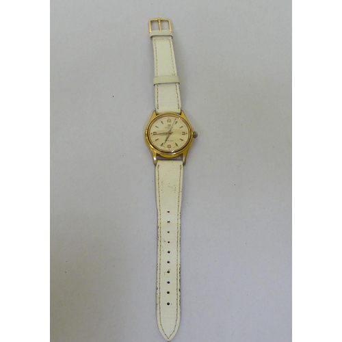 293 - A Roma gold plated, manual wind wristwatch, faced by a baton dial, on a white leather strap