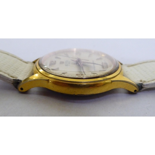 293 - A Roma gold plated, manual wind wristwatch, faced by a baton dial, on a white leather strap