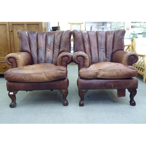 296 - A pair of modern Georgian reproduction red/brown hide upholstered, enclosed armchairs, raised on stu... 