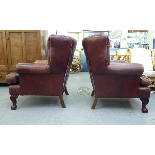 296 - A pair of modern Georgian reproduction red/brown hide upholstered, enclosed armchairs, raised on stu... 