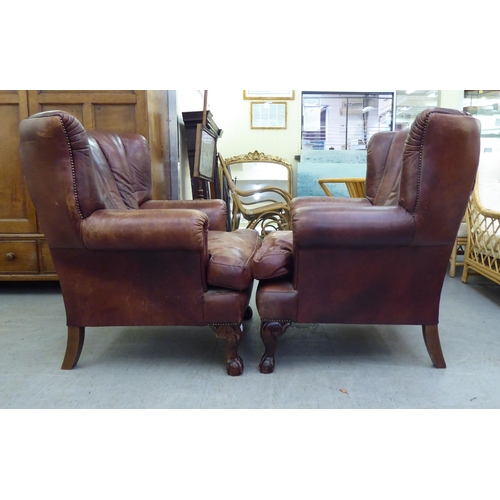 296 - A pair of modern Georgian reproduction red/brown hide upholstered, enclosed armchairs, raised on stu... 