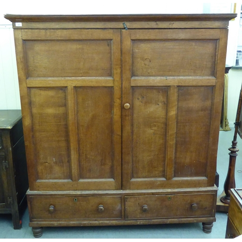 301 - A late 19thC oak cupboard with a pair of panelled doors, enclosing a shelved interior, over two draw... 