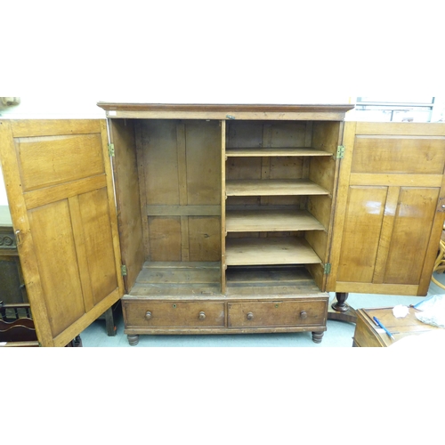 301 - A late 19thC oak cupboard with a pair of panelled doors, enclosing a shelved interior, over two draw... 