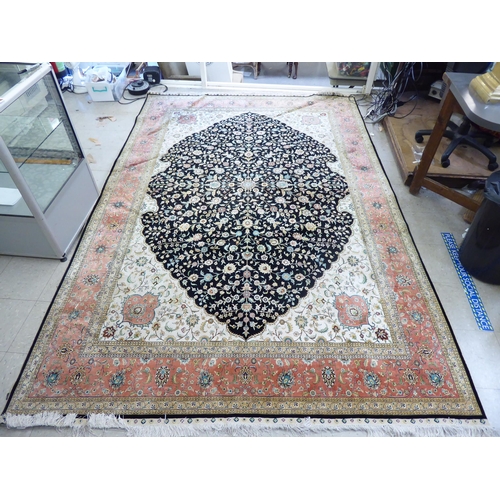 320 - An Asian part silk woven rug, decorated with floral designs, in a multitude of colours, on a black c... 