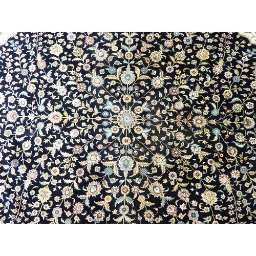 320 - An Asian part silk woven rug, decorated with floral designs, in a multitude of colours, on a black c... 