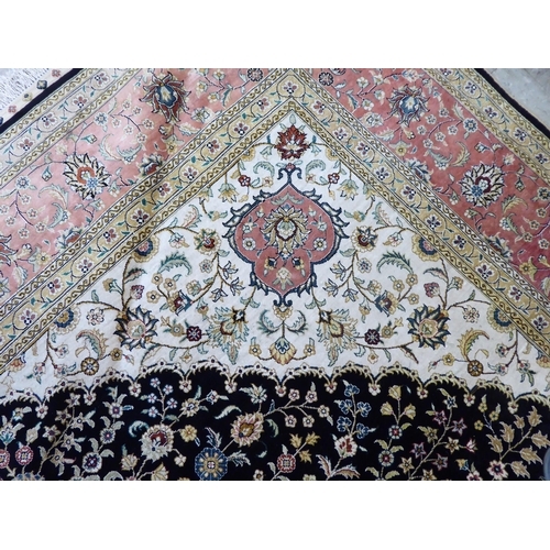 320 - An Asian part silk woven rug, decorated with floral designs, in a multitude of colours, on a black c... 