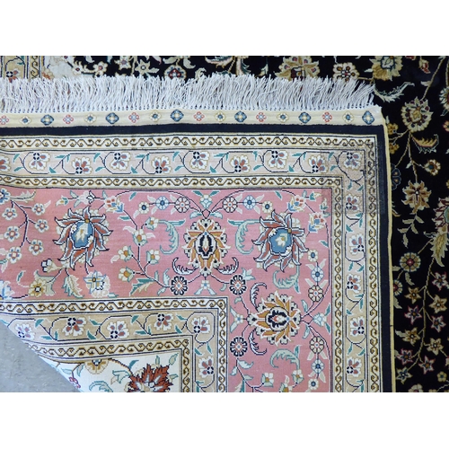 320 - An Asian part silk woven rug, decorated with floral designs, in a multitude of colours, on a black c... 