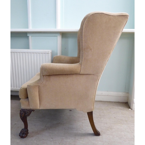 33 - A 1930s Georgian inspired, fabric upholstered, enclosed wingback armchair, raised on C-scroll and fo... 