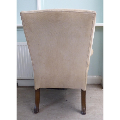 33 - A 1930s Georgian inspired, fabric upholstered, enclosed wingback armchair, raised on C-scroll and fo... 