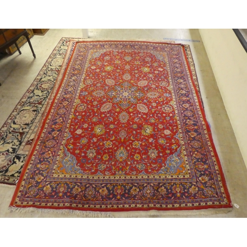 60 - A Central Persian rug, decorated with floral designs, on a mainly red ground  90