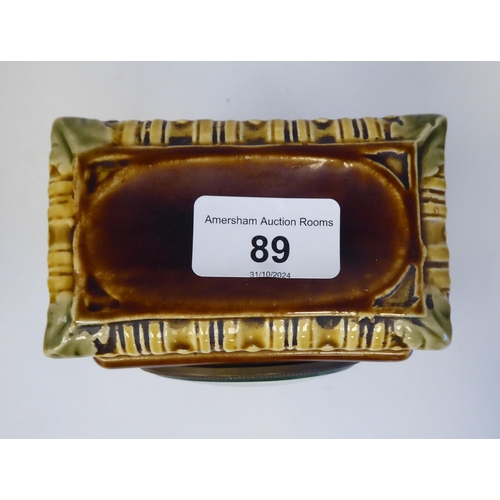 89 - An early 20thC Continental foliate moulded china, square cased mantel timepiece; faced by a brass an... 