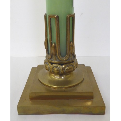 44 - An early 20thC brass table lamp incorporating an opaque, pale green glass column, on a stepped, squa... 